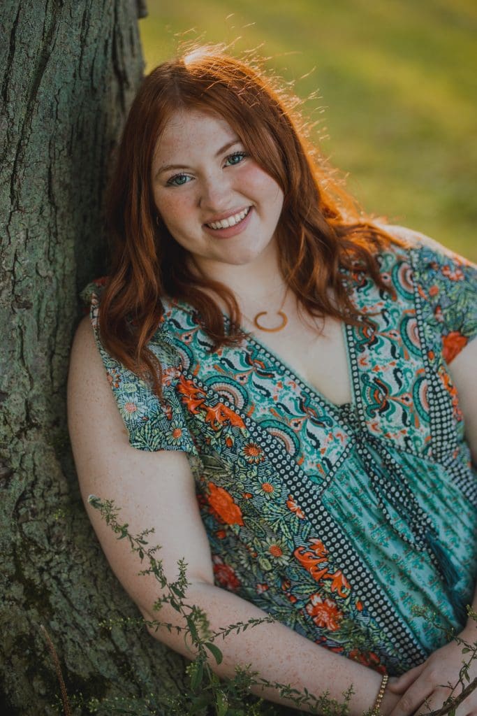 A photo of Caroline Parent, Social Media intern at the MSU Innovation Center learning against a tree