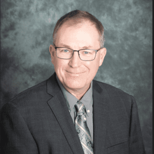 Ken Foster wearing a dark grey suit with a grey backdrop Technology Manager