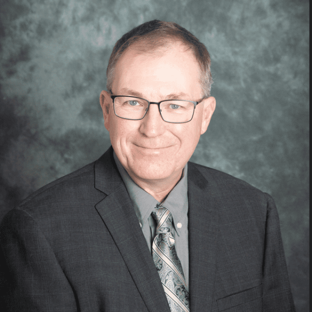 Ken Foster wearing a dark grey suit with a grey backdrop Technology Manager